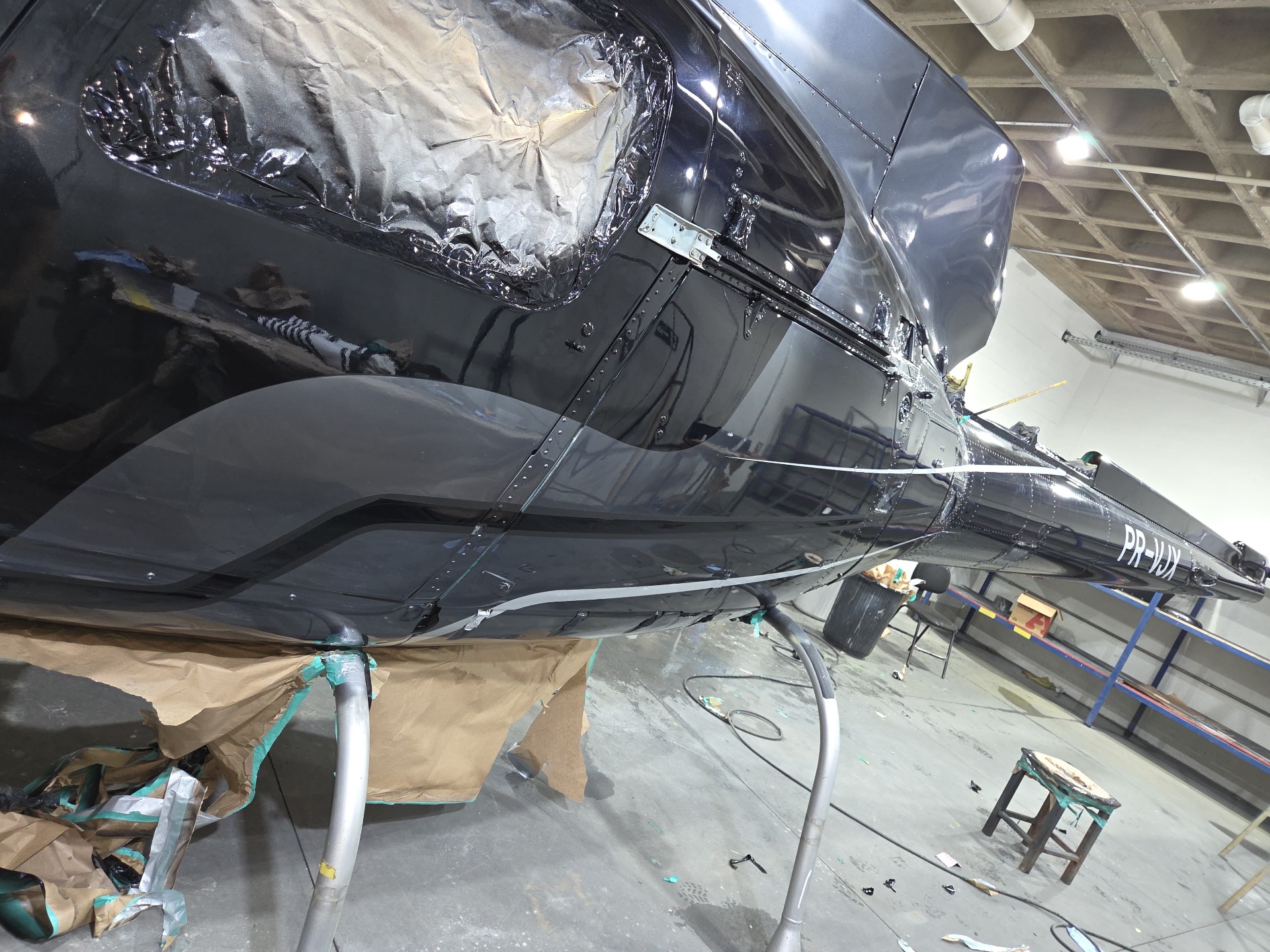 Detalhe da pintura do PR-VJX em execução no hangar, com janelas protegidas